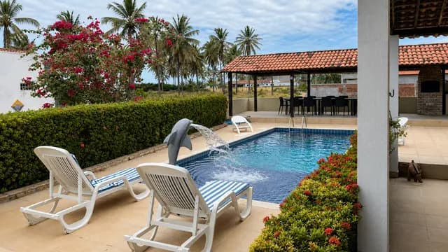 Piscina cercada por jardim e coqueiros